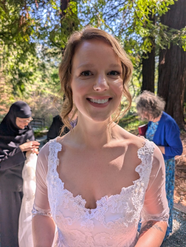 Anna before the ceremony, sister and aunt behind her tending to the dress.